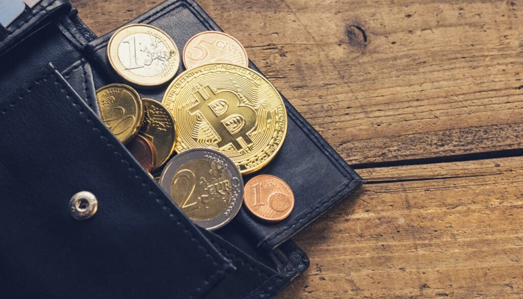 A bitcoin resting in a wallet placed on a wooden table, symbolizing digital currency and financial investment.