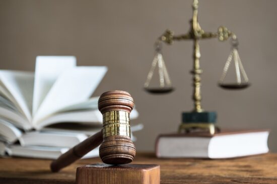 A gavel rests on a wooden table beside law books, symbolizing the concepts of law and justice.