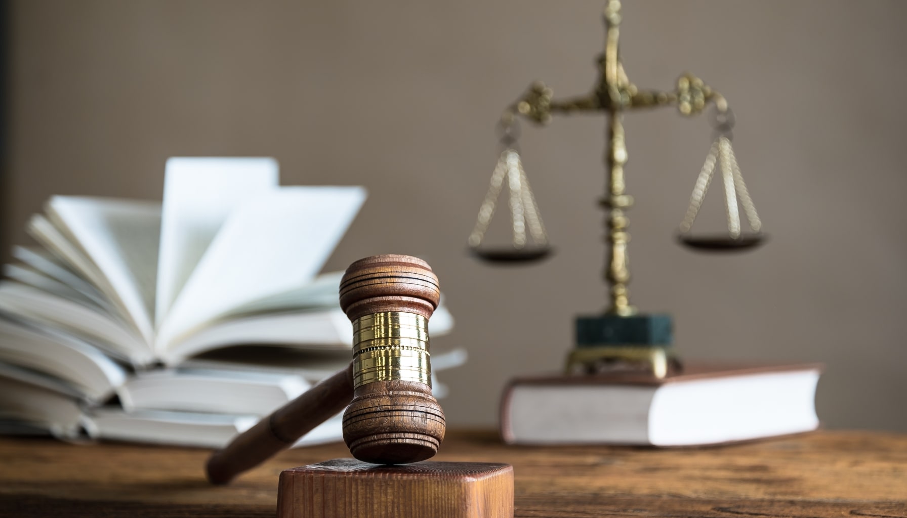 A gavel rests on a wooden table beside law books, symbolizing the concepts of law and justice.