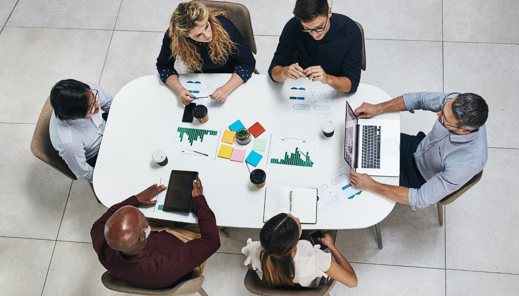 A diverse group of individuals collaborates around a table, each using their laptops for a productive meeting.