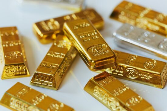 A pile of gold bars neatly arranged on a white surface, showcasing their shiny, metallic luster.