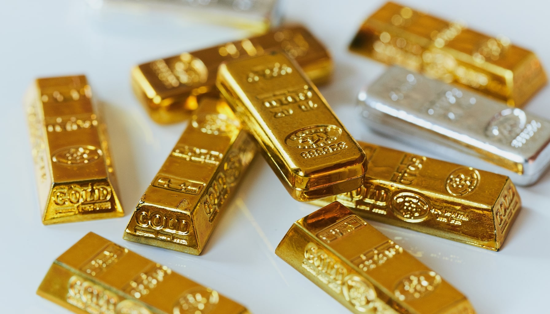 A pile of gold bars neatly arranged on a white surface, showcasing their shiny, metallic luster.