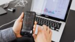 A man intently examines stock market data on his smartphone, showcasing modern investment practices