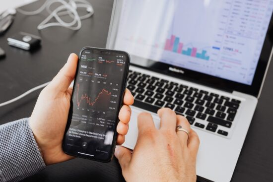 A man intently examines stock market data on his smartphone, showcasing modern investment practices