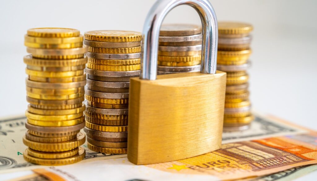 A golden padlock rests atop stacks of euro coins, symbolizing security and financial investment