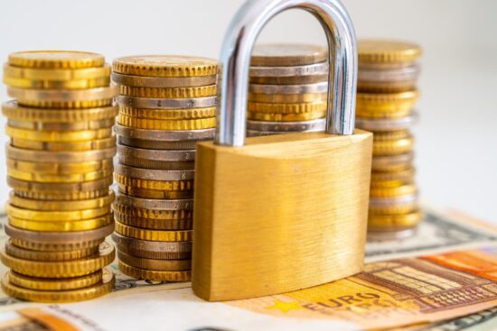 A golden padlock rests atop stacks of euro coins, symbolizing security and financial investment