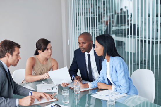 Business individuals collaborating and exchanging ideas in a well-lit meeting room.