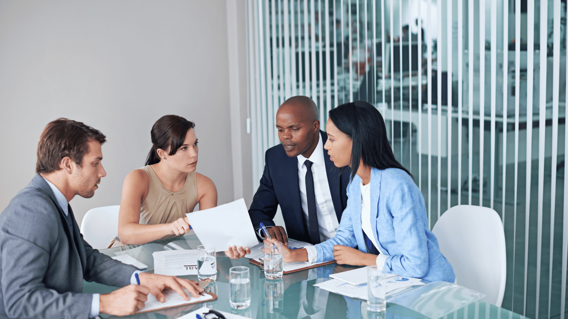 Business individuals collaborating and exchanging ideas in a well-lit meeting room.