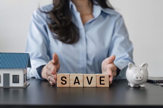 A woman is holding a block that displays the word "save," positioned on a table in a well-lit environment.