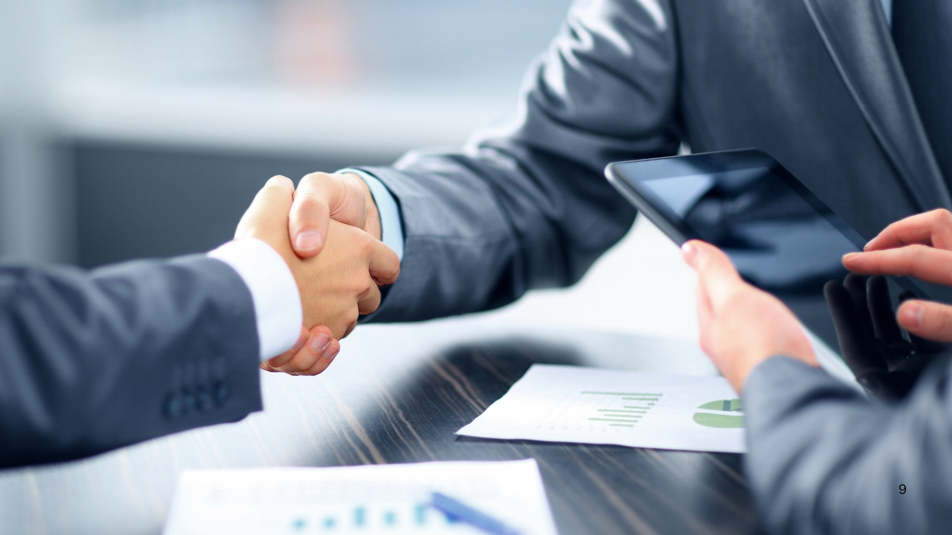 Two business professionals shaking hands over a conference table, symbolizing agreement and collaboration in a professional setting Banks.