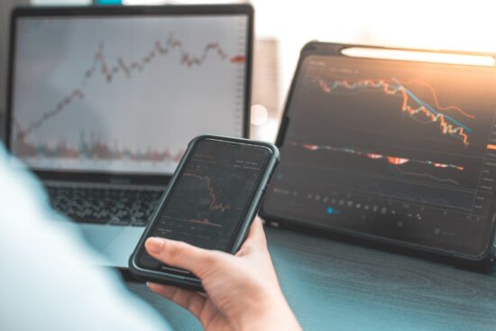 A laptop and smartphone displaying stock market trading charts and data, illustrating modern investment practices.