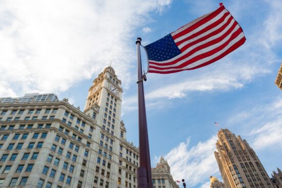 An American flag waves proudly in front of towering skyscrapers, symbolizing patriotism Trump's amidst urban architecture.