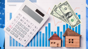 A calculator, wooden house models, and dollar bills on a financial analysis sheet with bar graphs and trend lines.